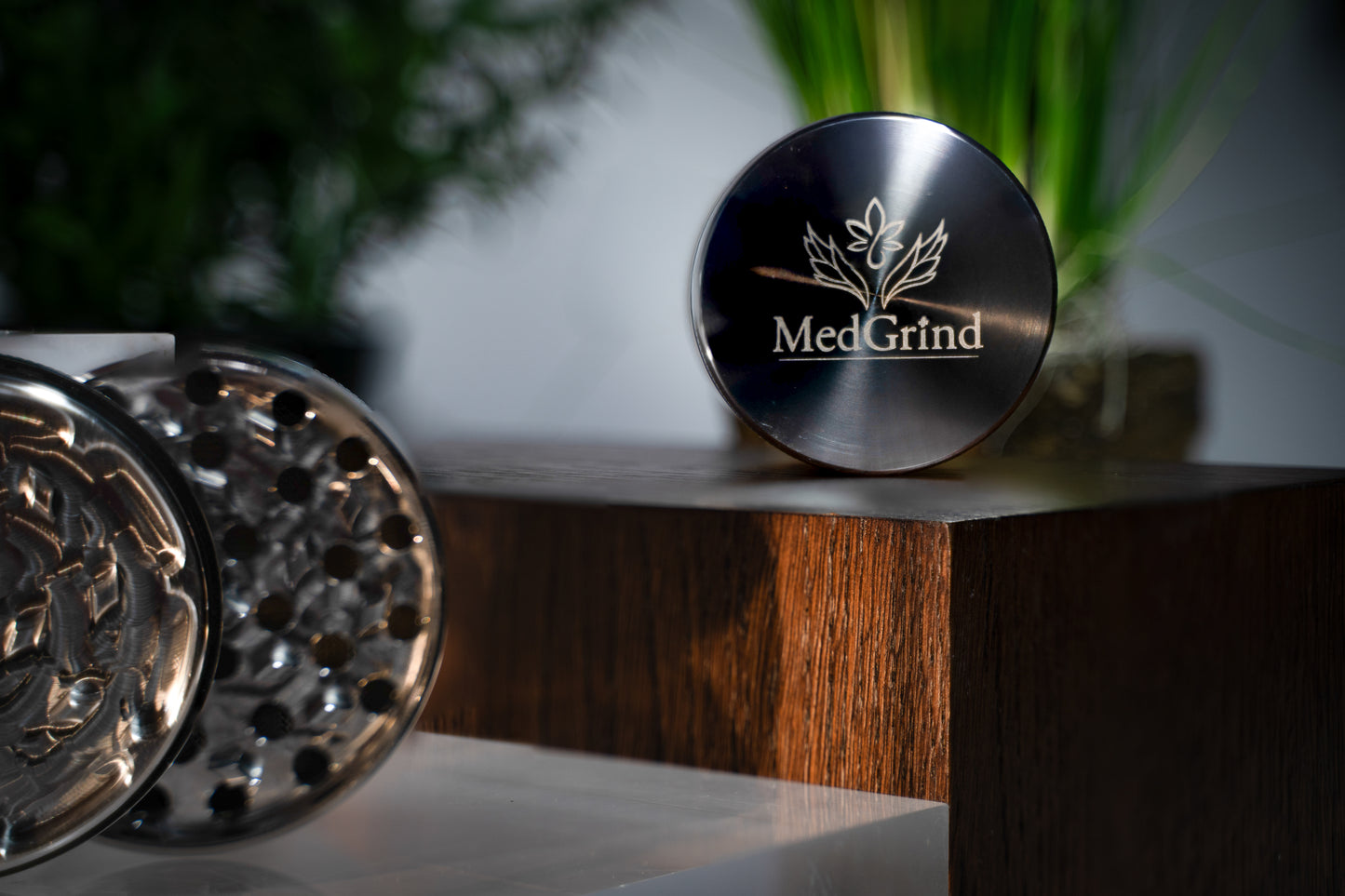 edGrind Premium Edelstahl Grinder – Deckel mit Logo und Mahlwerk aus passiviertem Edelstahl 304, langlebig, hygienisch, präsentiert auf Holzpodest mit Pflanzen