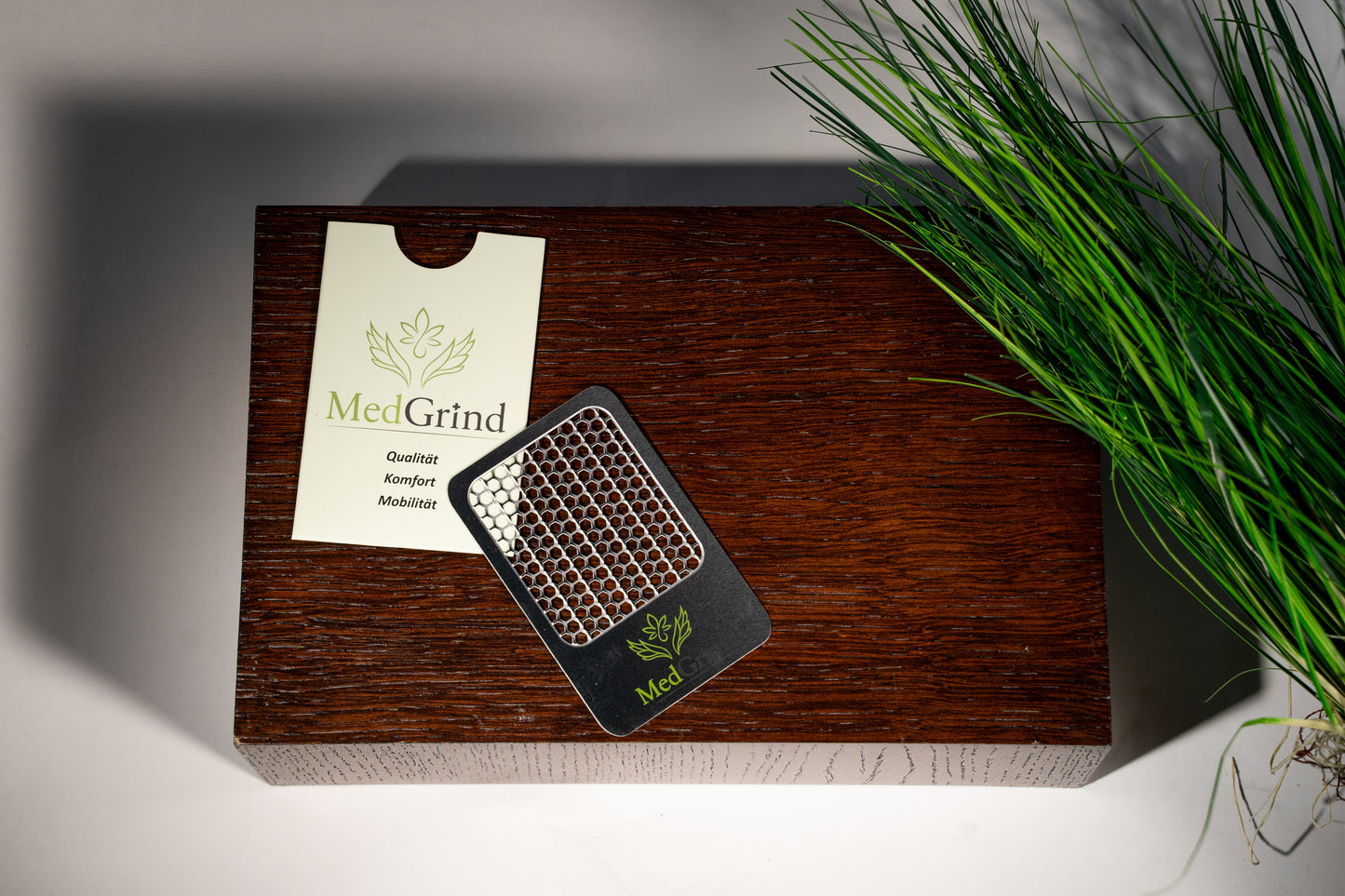 MedGrind Premium Edelstahl Grinder – austauschbares Sieb mit MedGrind Logo, passivierter Edelstahl 304, hochwertiges Zubehör auf Holzpodest mit Branding-Karte